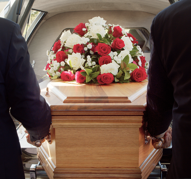 funeral directors carrying a coffin into a hearse